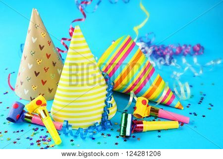 Three Birthday hats with serpentine streamer and noise makers on blue background