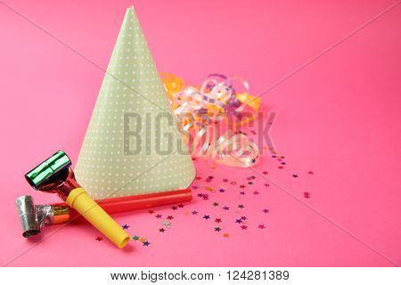 Dotted Birthday hat with serpentine streamer and noise makers on pink background