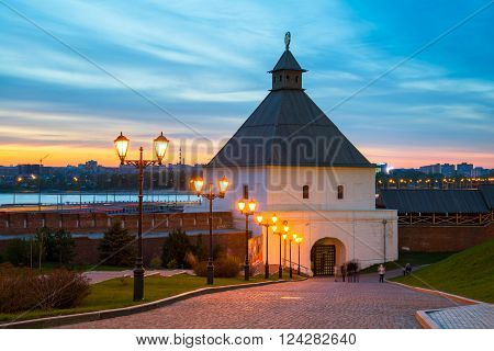 The illuminated Taynitskaya tower of the Kazan Kremlin at night with sunset sky.