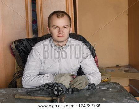 Man sitting at the table with drill and looking to camera
