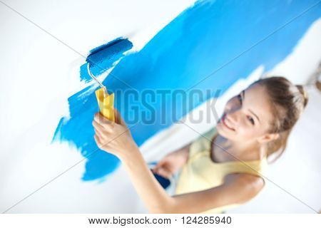 Happy beautiful young woman doing wall painting