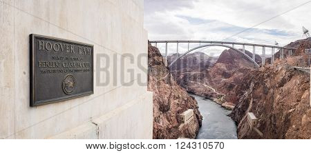 Plaque for Hoover Dam with the Pat Tillman bridge in the background.