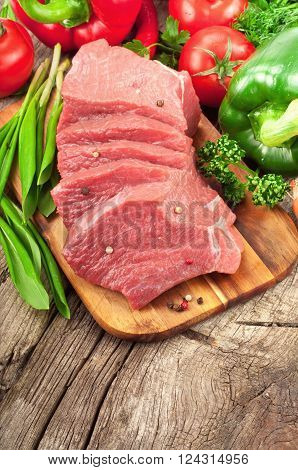 Fresh raw beef with vegetables on cutting board top view with copy space