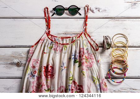 Flax sarafan and chameleon sunglasses. Female clothing on the table. Classy summer style for women. Look good and feel comfortable.
