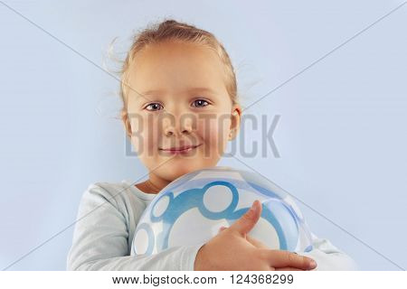 Summer. Adorable beautiful girl with ball against blue background. Summer background.
