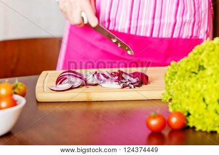 Woman cut red onion on cutting board