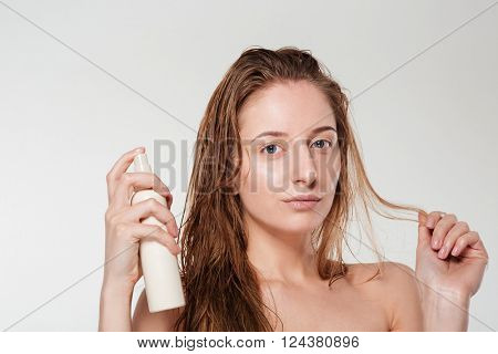 Beautiful woman spraying hairspray isolated on a white background