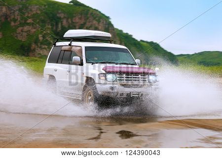 KHASAN RUSSIA - JULY 25 2015: Mitsubishi Pajero moving fast by water making lots of splashes