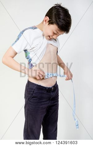 Young boy checking his wasit measurement with a tape measure