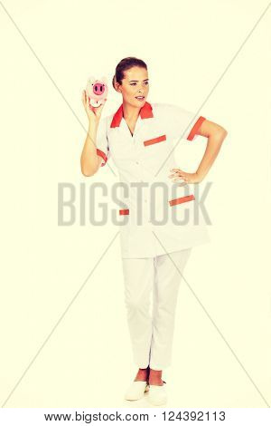 Young beautiful female doctor or nurse holding a piggybank