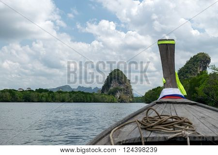 Traditional wooden boat against tropical river with Krabi landmark