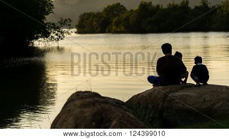 Songkhla Province, Thailand,  April 20, 2014 : Father daughter His son, sitting on the rocks in the Park