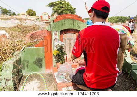 KUALA LUMPUR MALAYSIA April 2 2016: Chinese descendants cleaning tomb and offering prayers to ancestors during the annual QingMing or tomb sweeping day at cemetery in Malaysia