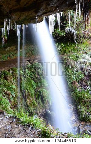 Icicles hang from the rock overhang under maspie den waterfall
