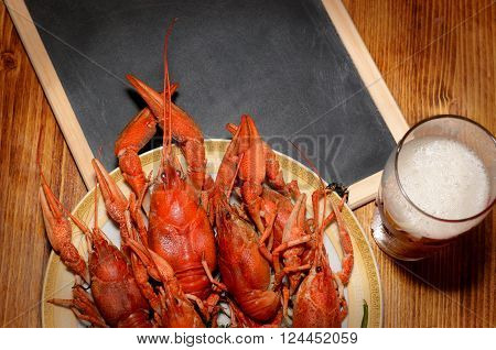 boiled crawfish, glass of light beer and black chalkboard top view picture
