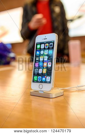 PARIS FRANCE - APR 4 2016: People testing new iPhone with the Apple iPhone SE in docking station during the sales launch of the latest Apple Inc. smartphone and iPad Pro at the Apple store in Paris France