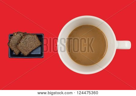 A hot dup of coffee and cake on a colored background