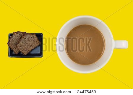 A hot dup of coffee and cake on a colored background