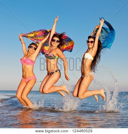Three beautiful girls having fun jumping on the beach on vacation