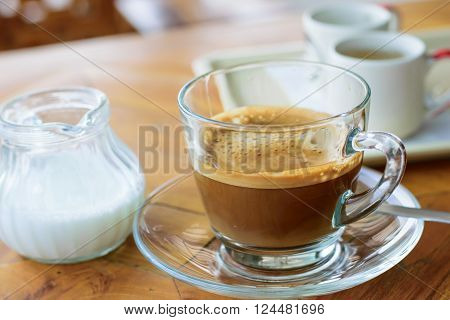 Morning cup of hot coffee with cream on table