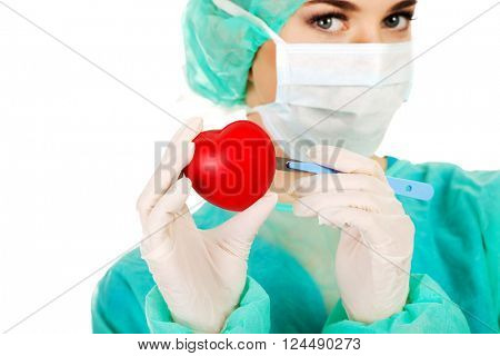 Young female cardiologist surgeron holding heart and scalpel