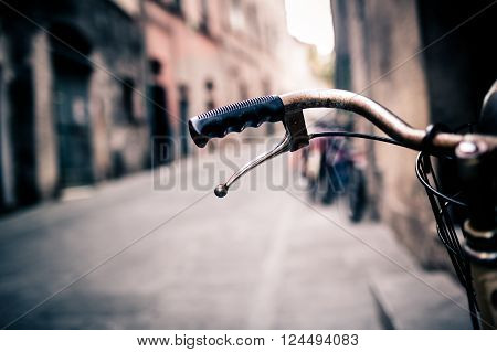 City old bicycle handlebar and basket over blurred background with narrow urban or town street. Vintage retro style bike with bokeh copy space.