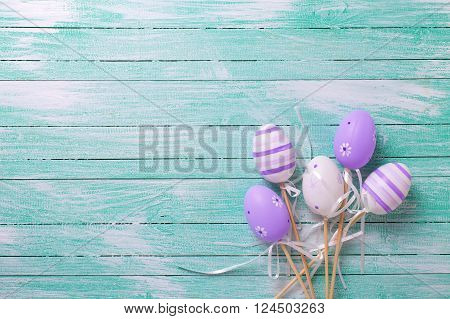 Easter/spring background. Decorative violet eggs on turquoise wooden background. Selective focus. Place for text.