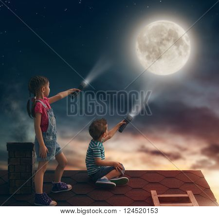 Two cute children sit on the roof and look at the moon.