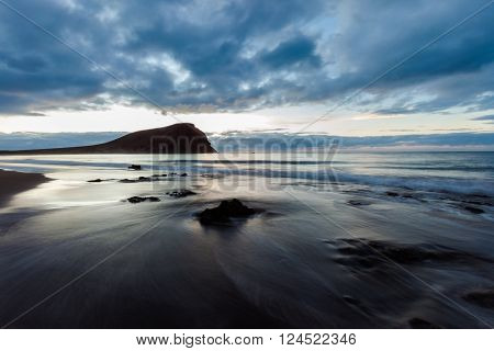 Summer sunrise seascape on tropical island Tenerife, Canary in Spain. Playa de La Tejita beach view on atlantic ocean and Punta Roja rock.