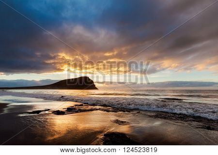 Summer sunrise seascape on tropical island Tenerife, Canary in Spain. Playa de La Tejita beach view on atlantic ocean and Punta Roja rock.