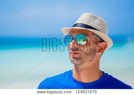 Portrait of a man in the sunglasses and hat on the beach