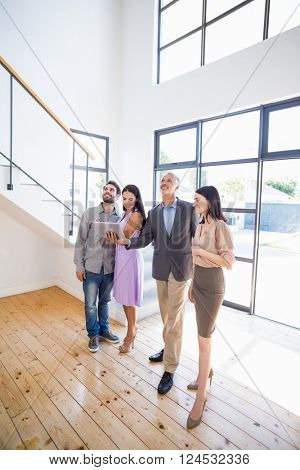 Real estate showing a house project on a digital tablet to young couple in their new home