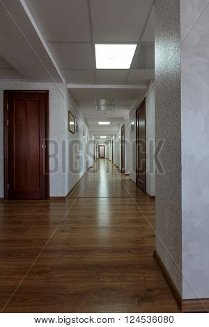 modern generic long office hallway with wooden floors and white painted walls