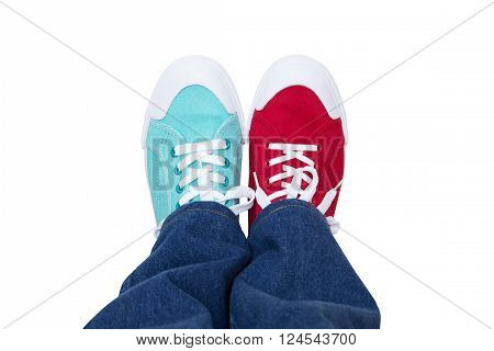 jeans and wearing different sneakers on legs