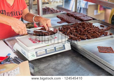GEORGE TOWN MALAYSIA - MARCH 23: Woman weigh Chinese dried pork at the street market on March 23 2016 on George Town Malaysia.