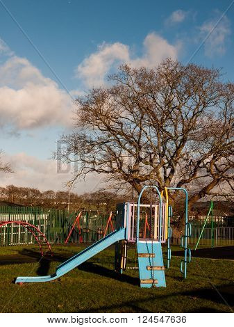 An empty park containing a slide swings and climbing frame.