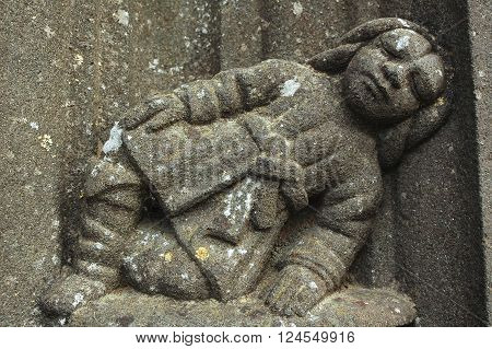Guimiliau (Finistere Brittany France): the medieval church with the typical stone calvary. A statue.