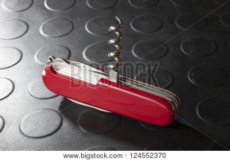 Red pocketknife with its corkscrew out and ready to use