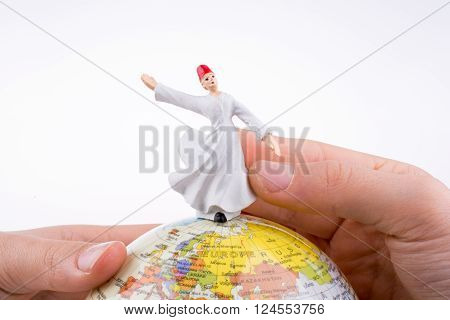 Hand holding a Sufi Dervi? on a globe
