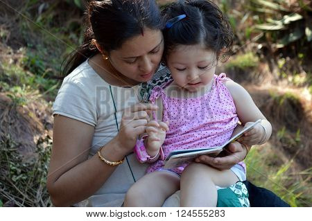 Mother reading book with her 2 year old child.