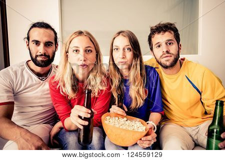 Young attractive people watching TV at home - Group of friends looking at something dramatic on television
