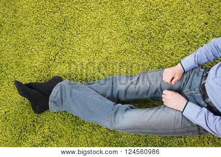 young man sitting on a green carpet with tablet