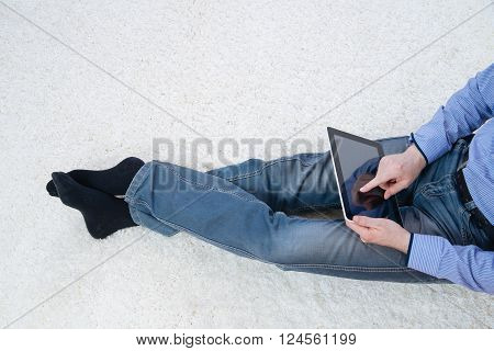 young man sitting on a white carpet with tablet