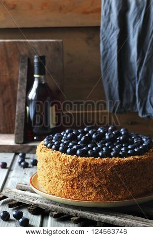 Homemade honey cake decorated with blueberry on a wooden background