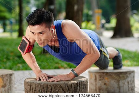 Sweaty determined young Vietnamese sportsman doing push-ups