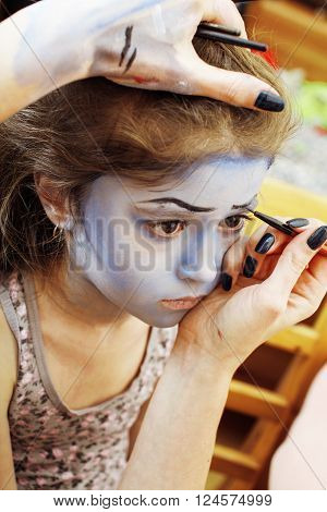 little cute child making facepaint on birthday party, zombie Apocalypse facepainting, halloween preparing concept at home