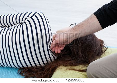 Reflexology. Man's hand manipulates on the woman's neck by the knuckles woman lays on the mat