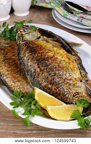 Fried crucian carp in a plate on the table closeup