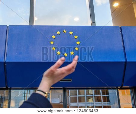 STRASBOURG, FRANCE - DECEMBER 2015:Woman hands trying to hold the stars of European Union insignia in front of the Council of Europe entrance
