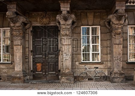 Bicycle parked beside building with statues of atlantes in old European city